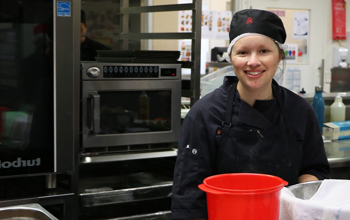 Woman smiles wearing food service attire