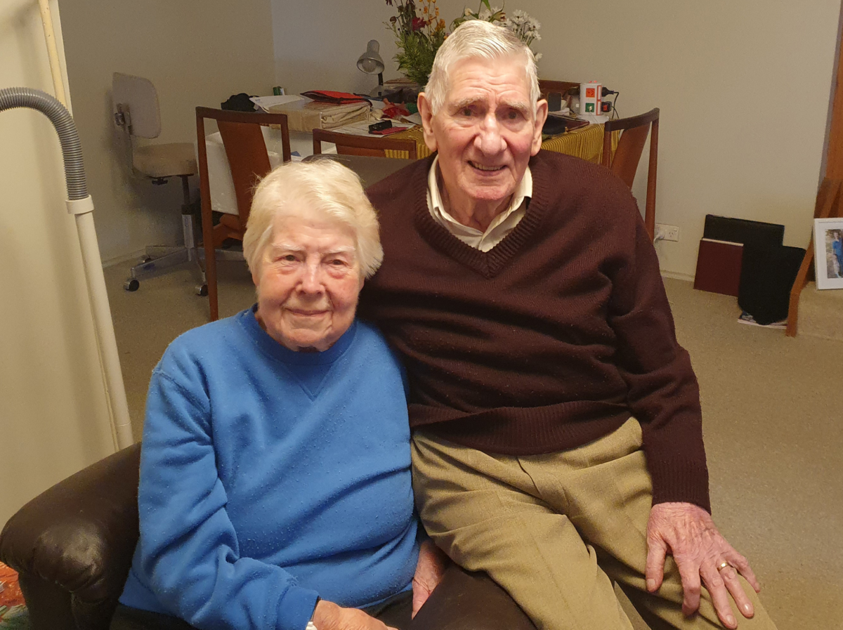 Elderly couple sitting down posing for photograph