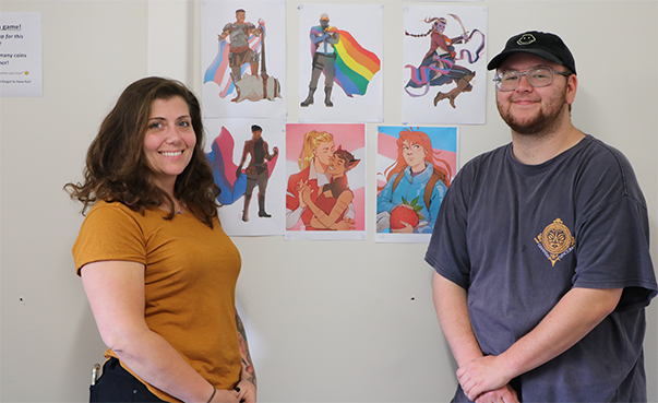 two people smiling standing in front of wall with rainbow character drawings