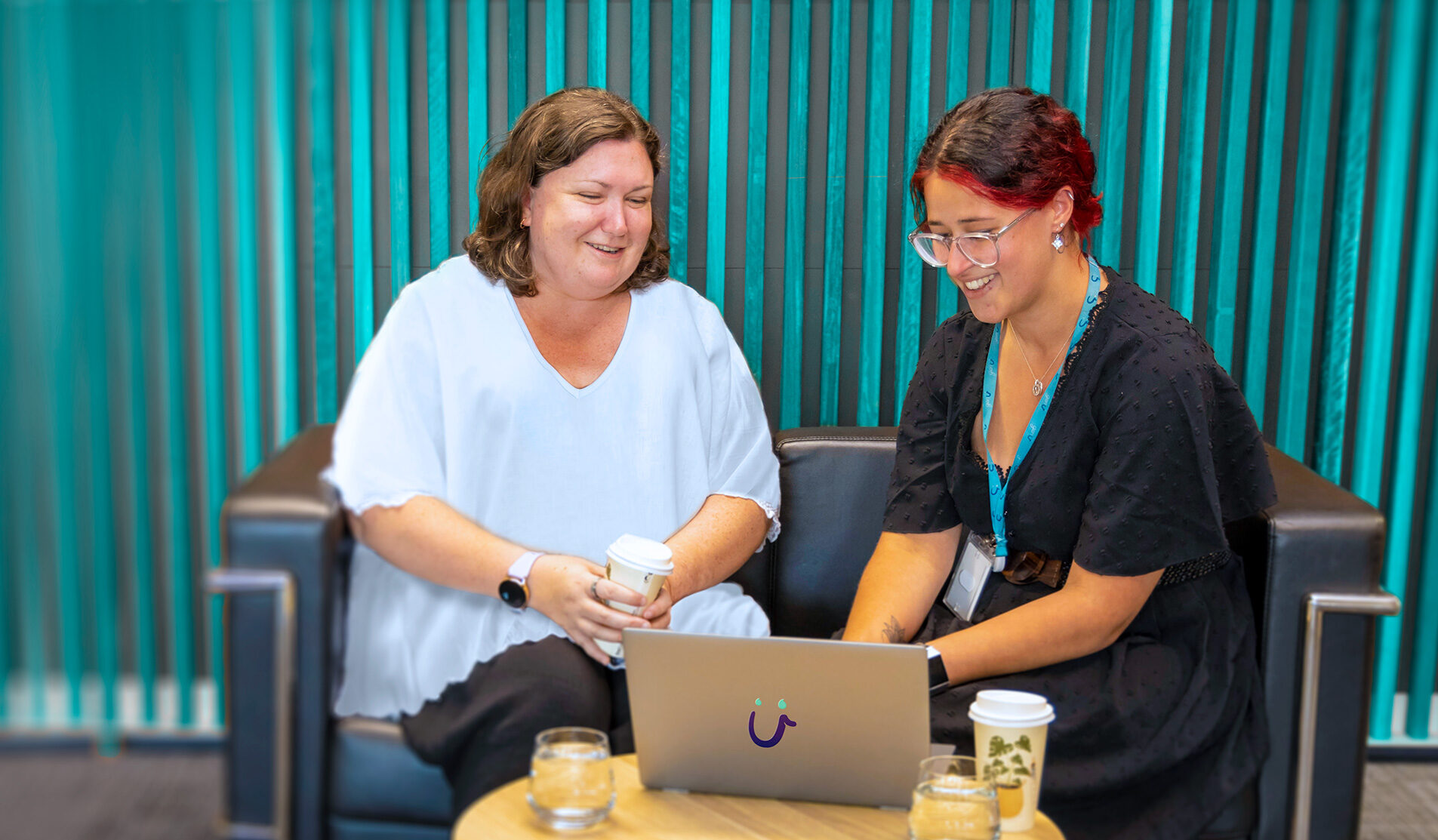 Two women looking at a laptop on a table and having a conversation