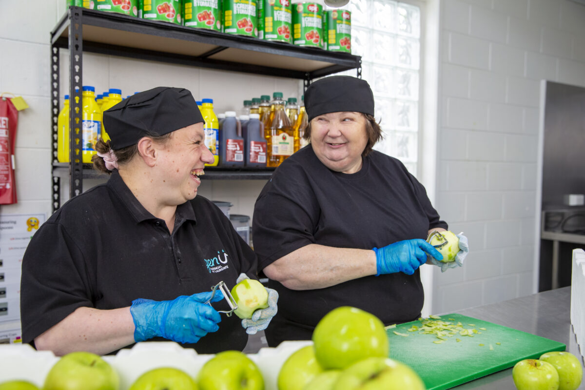 Kerrie working with another supported employee peeling green apples in the Rosebud Seasons kitchen.