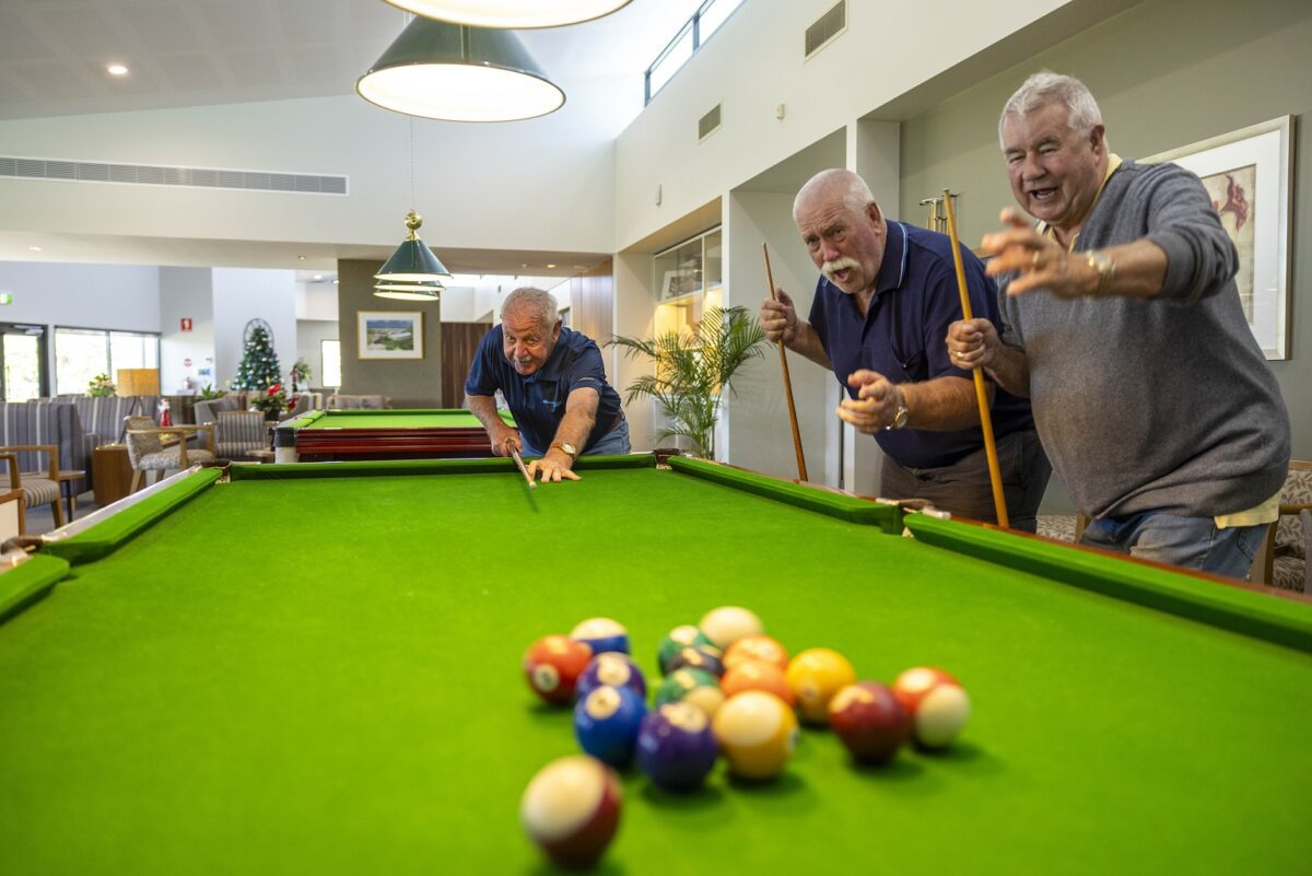 Three older men are playing billiards in the shared community space at Barwarre Gardens