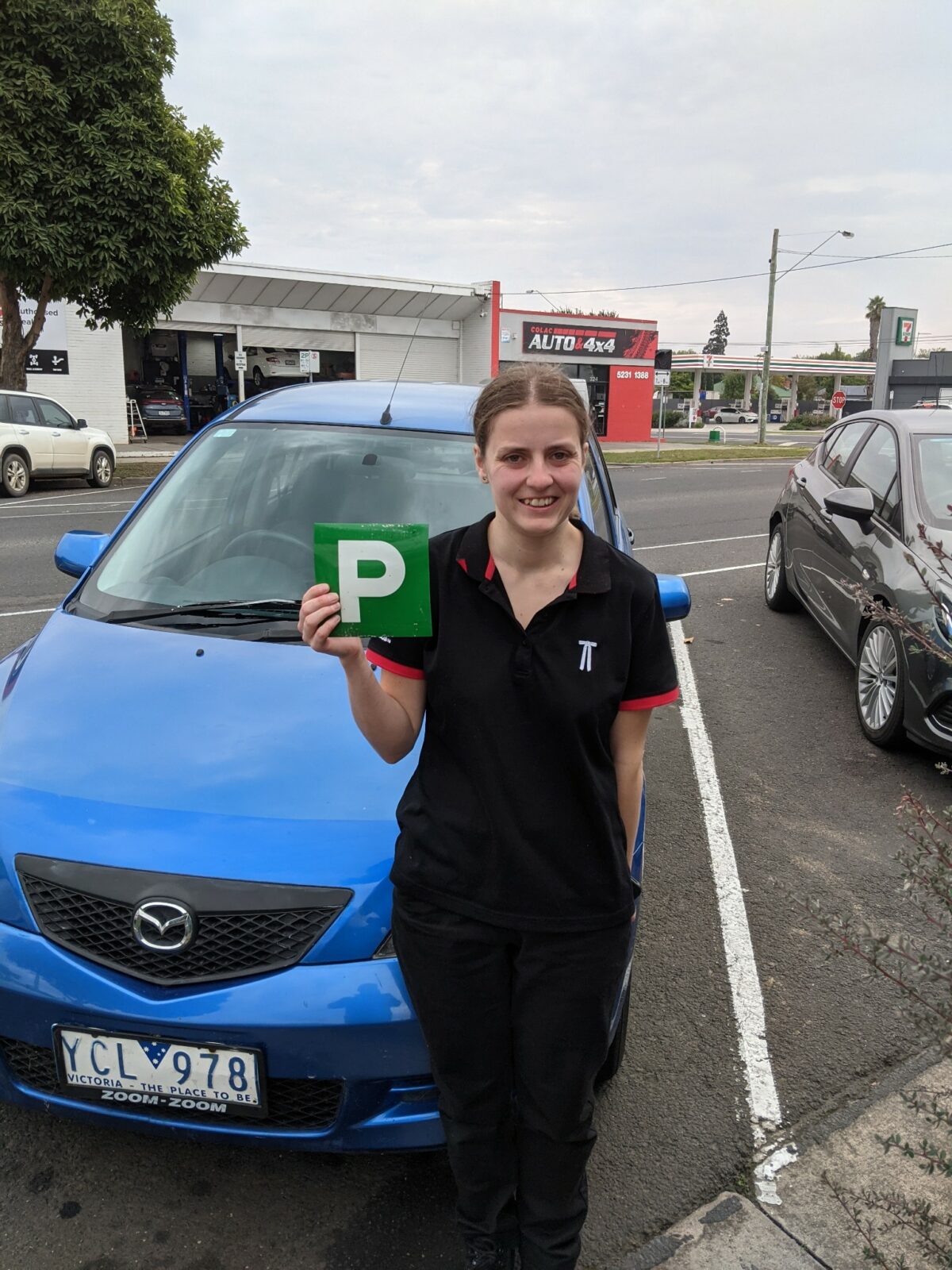 women standing next to new car holding up P plate after gaining license