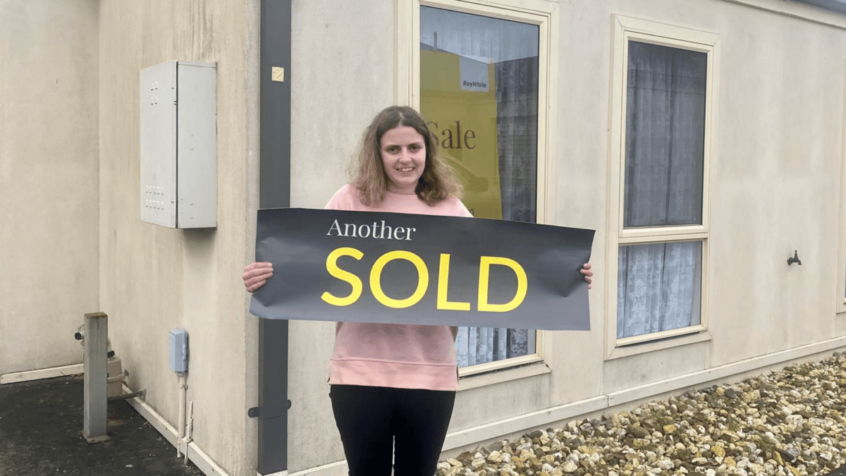 women standing outside newly purchased home with sold sign